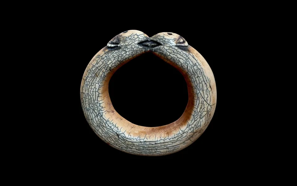 Carved bangle with two heads meeting, on black